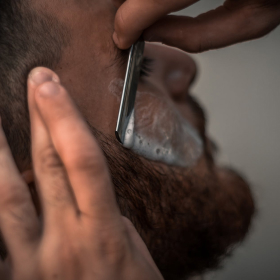 barber makes shaving of beard using his dangerous razor